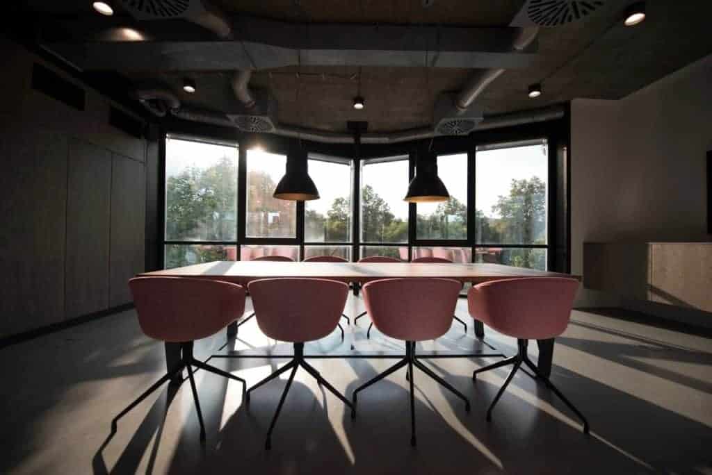 Photo of empty pink chairs around a table.